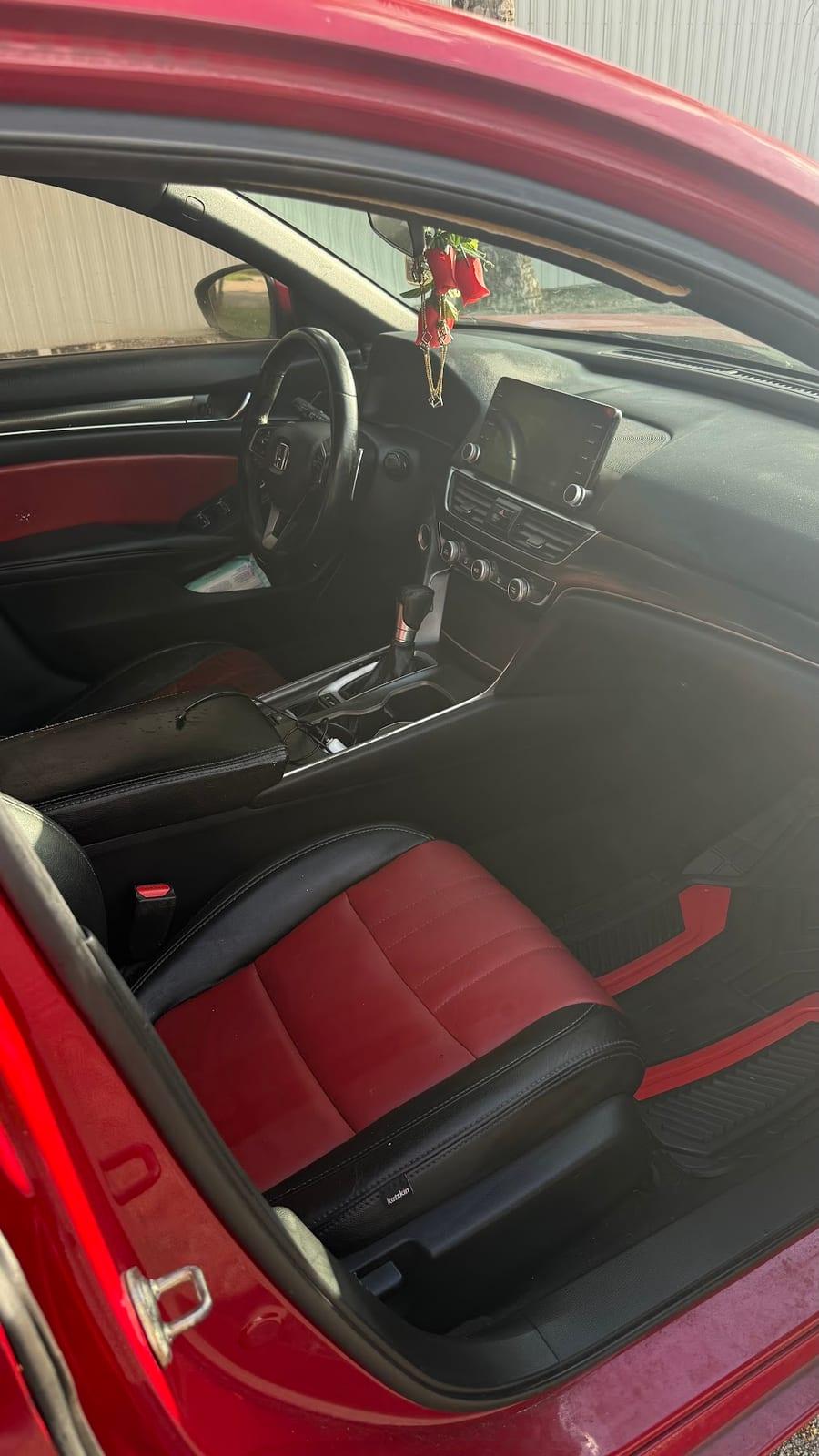 The same Honda sedan front interior after detailing, with clean carpet and floor area, a dust-free dash and center console, and red-and-black leather seats wiped down to an even matte finish.
